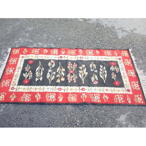 524 - A bordered Kelim with floral design on a black central field, red ground border, 6ft x 3ft 1in