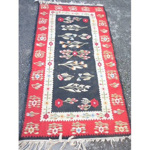 524 - A bordered Kelim with floral design on a black central field, red ground border, 6ft x 3ft 1in