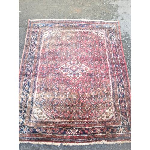 525 - A bordered Hamadan type Rug with central stepped medallion surrounded by stylised flowers on a red g... 