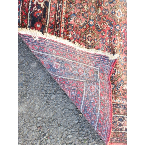 525 - A bordered Hamadan type Rug with central stepped medallion surrounded by stylised flowers on a red g... 