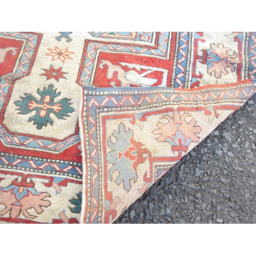 527 - A bordered Kazak type Rug with central star medallion with latch hooks on a camel, red and blue grou... 