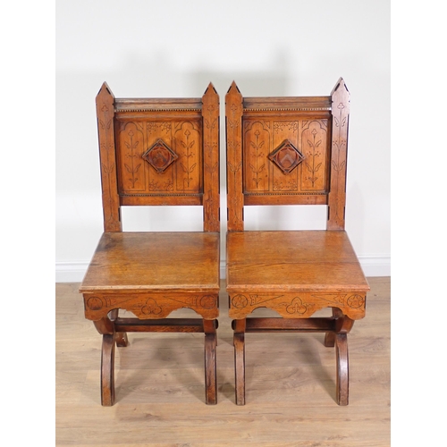 555 - A pair of Arts and Crafts Hall Chairs with arched back supports, carved incised stylised floral desi... 