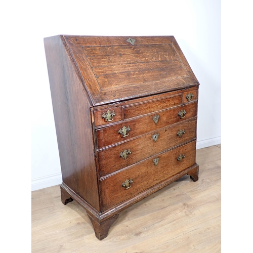 607 - A George III oak Bureau with fielded fall front enclosing pigeon holes and drawers above two short a... 