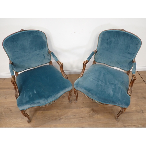 614 - A pair of French Elbow Chairs with floral carving to the arched top rail, shaped arms on slender cab... 