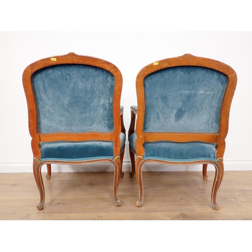 614 - A pair of French Elbow Chairs with floral carving to the arched top rail, shaped arms on slender cab... 