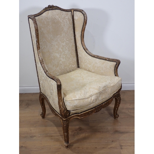 626 - A 19th Century gilt framed winged Armchair on carved cabriole leg supports, upholstered in cream dam... 