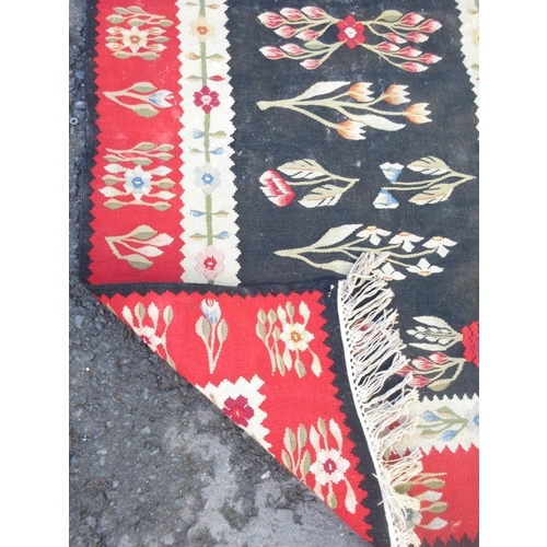 524 - A bordered Kelim with floral design on a black central field, red ground border, 6ft x 3ft 1in