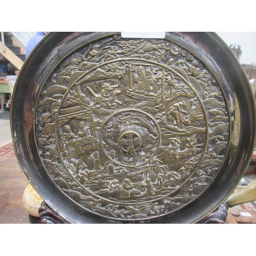 426 - An Oriental bronze Plaque depicting numerous figures in a landscape, 11 1/2in diam, raised on a carv... 