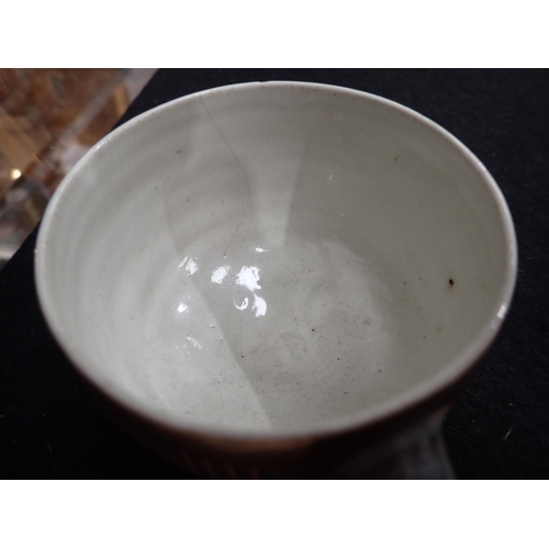 375 - Two Lucie Rie Cups and Saucer in a brown glaze with cream trellis designs, loop handles to the bulbo... 