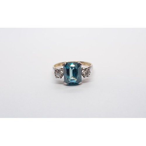 157 - ** WITHDRAWN ** A Blue Zircon and Diamond three stone Ring corner claw-set step-cut zircon between t... 