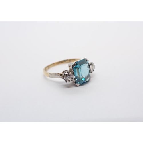 157 - ** WITHDRAWN ** A Blue Zircon and Diamond three stone Ring corner claw-set step-cut zircon between t... 