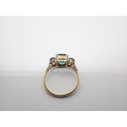 157 - ** WITHDRAWN ** A Blue Zircon and Diamond three stone Ring corner claw-set step-cut zircon between t... 