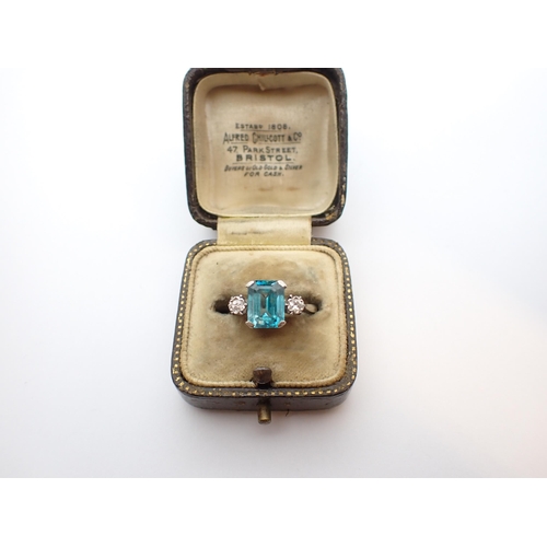 157 - ** WITHDRAWN ** A Blue Zircon and Diamond three stone Ring corner claw-set step-cut zircon between t... 