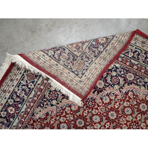 257 - A Persian style Rug with multiple borders, floral motifs on a red ground, 9ft 4in x 5ft 10in