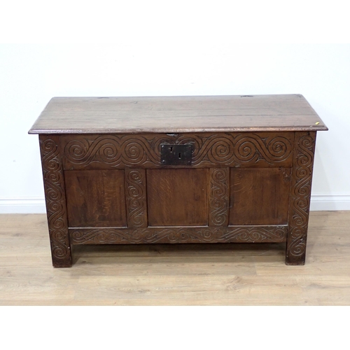 628 - An 18th Century oak Coffer with moulded plank lid above three panel front surrounded by scroll carvi... 