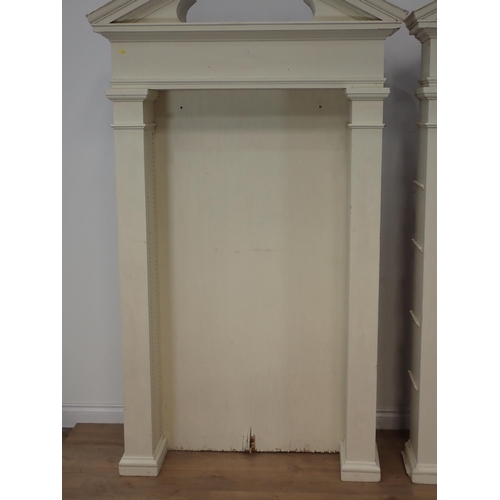 678 - A pair of cream painted architectural Bookcases with broken pediments lacking adjustable shelves 7ft... 