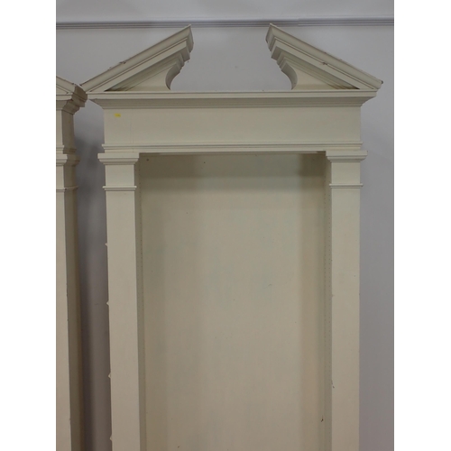 678 - A pair of cream painted architectural Bookcases with broken pediments lacking adjustable shelves 7ft... 