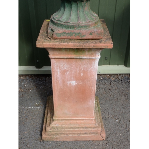 710 - A terracotta urn on pedestal with semi lobed design, with masks to the sides, possibly depicting Que... 