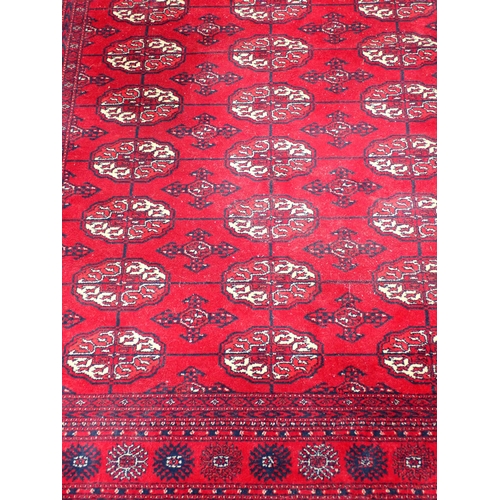 736 - A red ground Persian Rug with three rows of medallions within tramline borders 6ft 10in L x 4ft 8in ... 