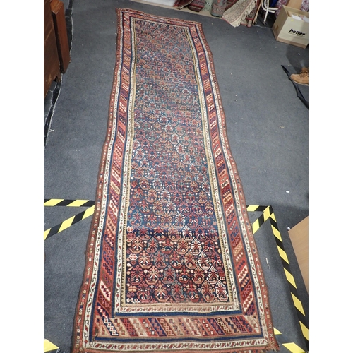 743 - An indigo ground Persian Rug with stylised flowers within striped tramline border 12ft L x 3ft 8in W