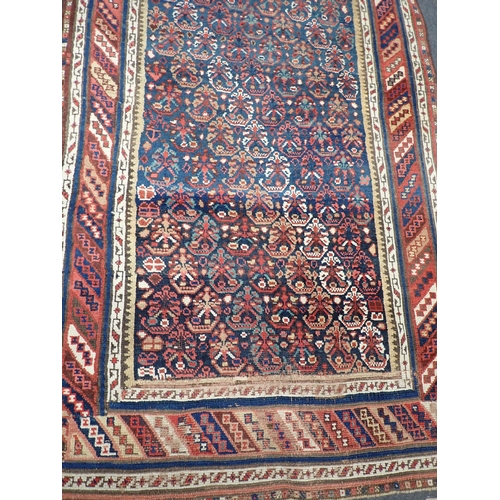 743 - An indigo ground Persian Rug with stylised flowers within striped tramline border 12ft L x 3ft 8in W