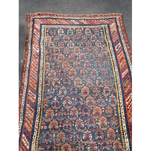 743 - An indigo ground Persian Rug with stylised flowers within striped tramline border 12ft L x 3ft 8in W