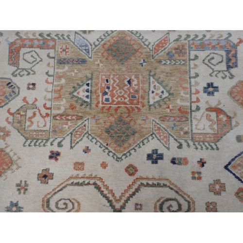 76 - A Kabir cream Rug with shapes and stylised flowers within apricot border 9ft 6in L x 6ft 6in W