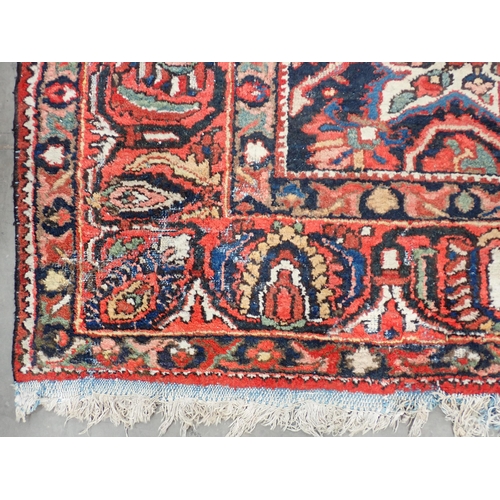 77 - A Persian red ground woollen Carpet with large central lotus flower design amongst stylised flowers ... 