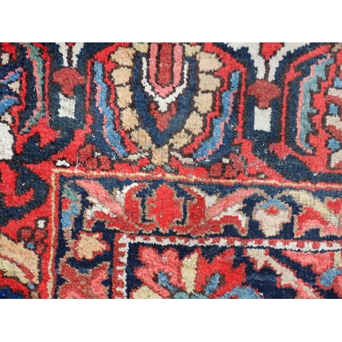 77 - A Persian red ground woollen Carpet with large central lotus flower design amongst stylised flowers ... 