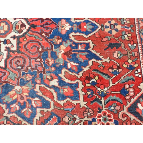 77 - A Persian red ground woollen Carpet with large central lotus flower design amongst stylised flowers ... 