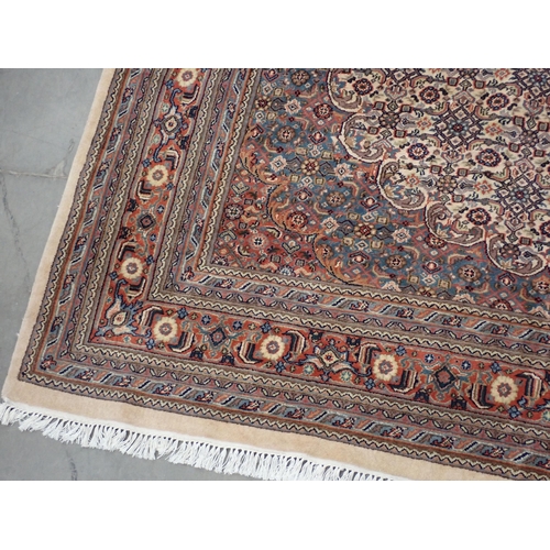 78 - A modern Indo Chahkari Carpet with stylised floral design on cream oval ground within red and blue m... 