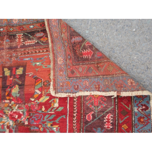 80 - An old bordered Persian Rug with stylised floral and leafage design on a red ground, 7ft 3in x 5ft 3... 