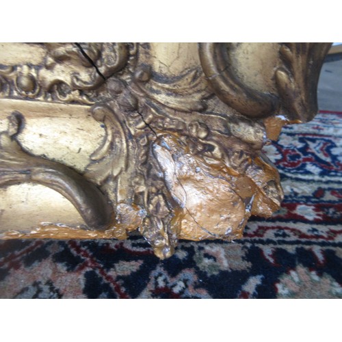 763 - A gilt framed Wall Mirror with elaborate scrolled and floral frame, A/F, 3ft 7in  x 2ft 11in