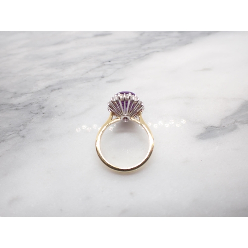 173 - An Amethyst and Diamond Cluster Ring claw-set oval mixed-cut amethyst, 3.14cts, within a frame of fo... 