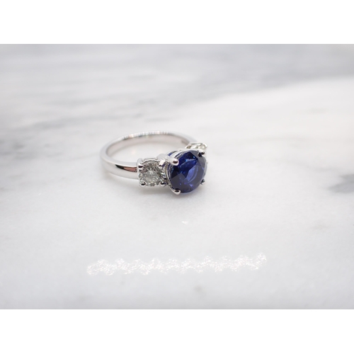 174 - A Sapphire and Diamond three stone Ring claw-set round sapphire, 2.65cts, between two brilliant-cut ... 