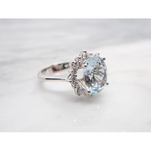 192 - An Aquamarine and Diamond Cluster Ring claw-set oval mixed-cut aquamarine, 4.70cts, within a frame o... 