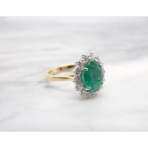 193 - An Emerald and Diamond Cluster Ring claw-set oval-cut emerald, 2.78cts, within a frame of fourteen b... 