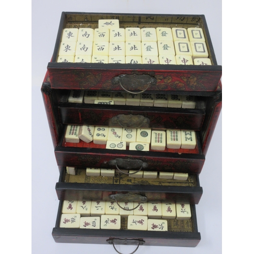 49 - A Mah Jong Set in red lacquered case with slide-up front revealing four drawers, 8in