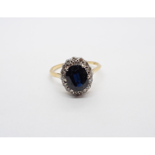 169 - A Sapphire and Diamond Cluster Ring claw-set oval-cut sapphire within a frame of illusion-set eight-... 