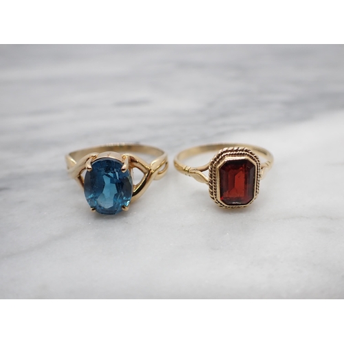 164 - A 9ct gold Dress Ring claw-set oval-cut blue topaz and a 9ct gold Ring rubover-set step-cut garnet, ... 