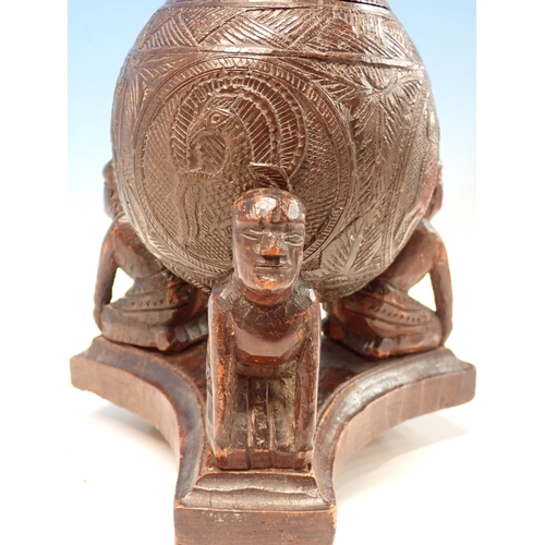 269 - An antique carved Coconut Shell with lid resting upon three kneeling African tribal figures 8in