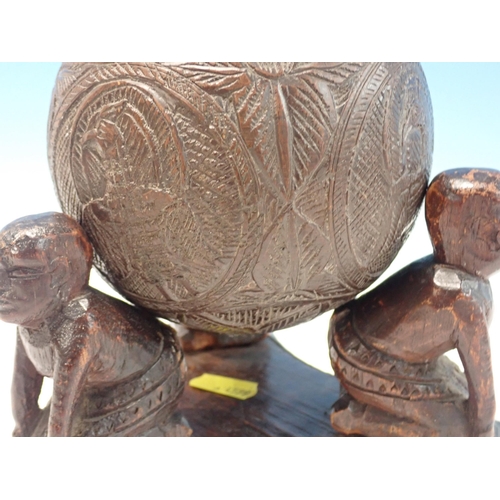 269 - An antique carved Coconut Shell with lid resting upon three kneeling African tribal figures 8in