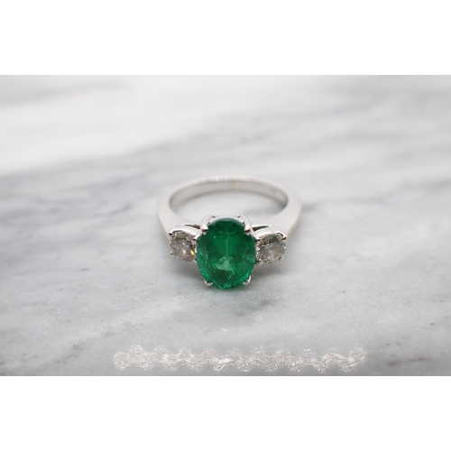 63 - An Emerald and Diamond three stone Ring claw-set oval-cut emerald between two brilliant-cut diamonds... 