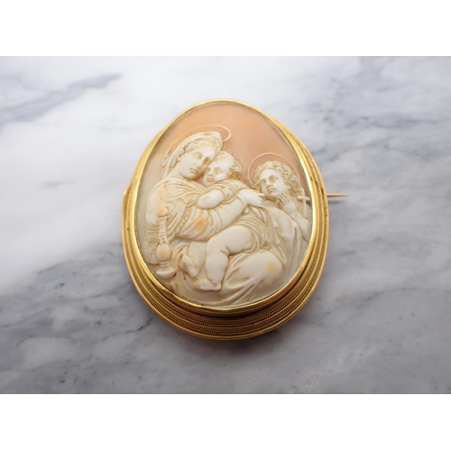 72 - A carved Shell Cameo Brooch in yellow metal frame depicting Madonna and child with John the Baptist.... 