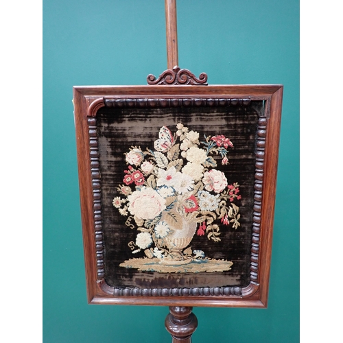 436 - A 19th Century rosewood Polescreen with floral needlework panel on turned tapering and carved column... 