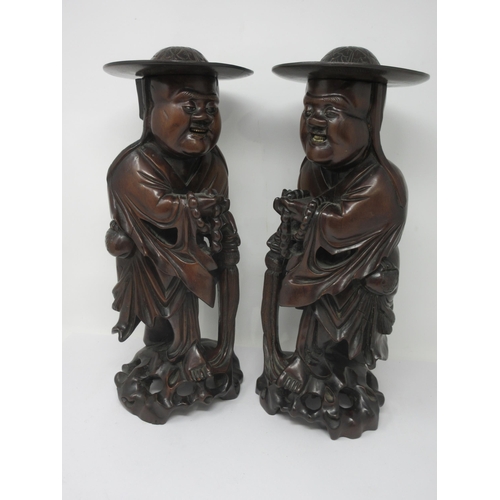 349 - A pair of Oriental carved hardwood Figures of Chinamen wearing flowing robes and leafage carved cool... 