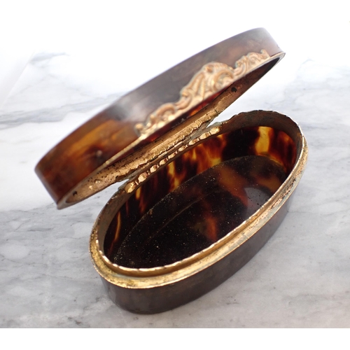 131 - A19th Century oval tortoiseshell Snuff Box the lid inlaid flowers with yellow metal mounts, 3 1/2in