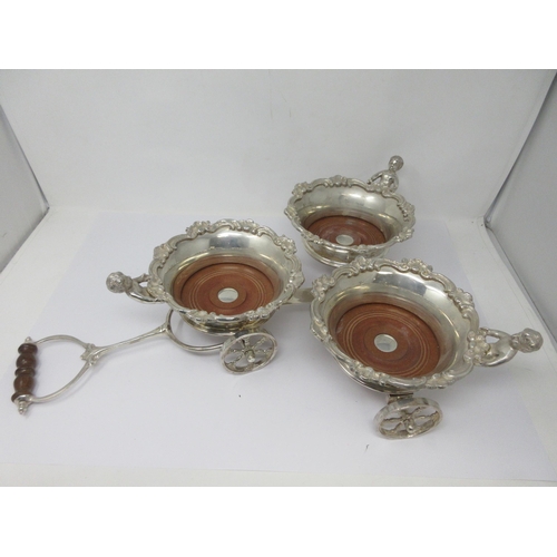 209 - A plated Decanter Wagon with three circular Coasters, having scroll borders, cherub supports, turned... 