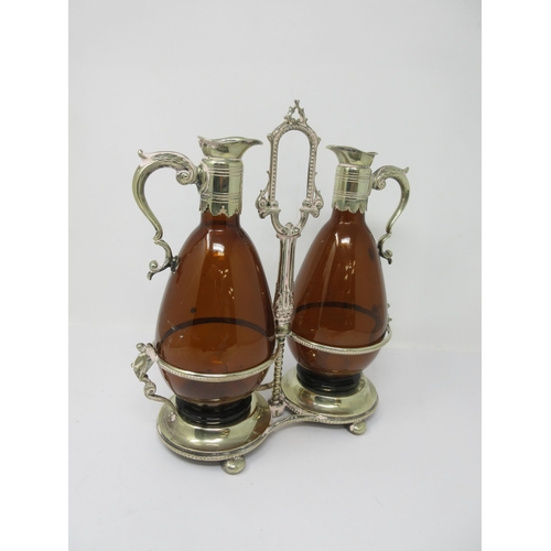 211 - A pair of amber glass Claret Jugs with plated mounts, scroll handles on a plated stand with central ... 