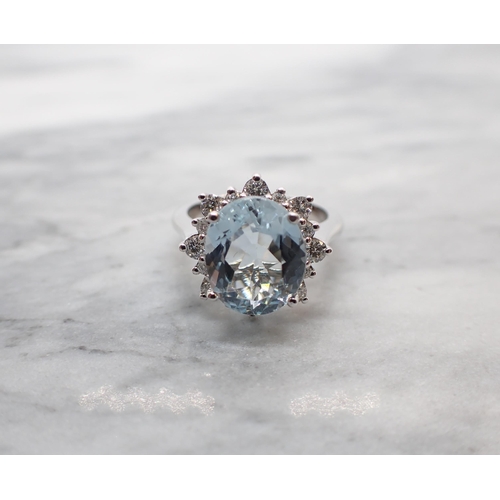 38 - An Aquamarine and Diamond Cluster Ring claw-set oval-cut aquamarine, 4.70cts, within a starburst fra... 